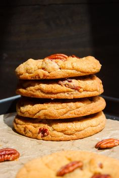 a stack of cookies sitting on top of a pan filled with pecanse and nuts