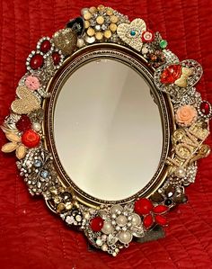 a mirror that is sitting on top of a red blanket with buttons and other things around it