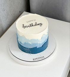 a white and blue birthday cake sitting on top of a refrigerator freezer with the words happy birthday written on it