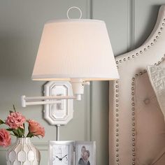 a white lamp sitting on top of a table next to a vase filled with flowers