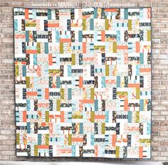 an orange and blue quilt hanging on a brick wall