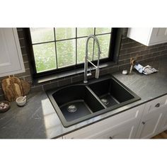 a kitchen sink sitting under a window next to a faucet and counter top