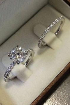 two engagement rings sitting in a box on top of a table