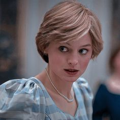 a woman in a blue and white striped dress looking at the camera with a surprised look on her face