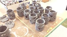 many clay cups sitting on top of a table next to cans and other items in the background