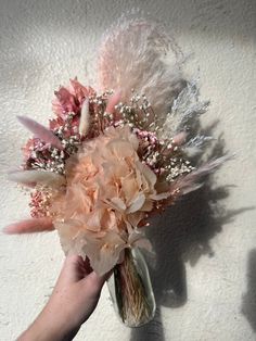 a person holding a bouquet of flowers and feathers