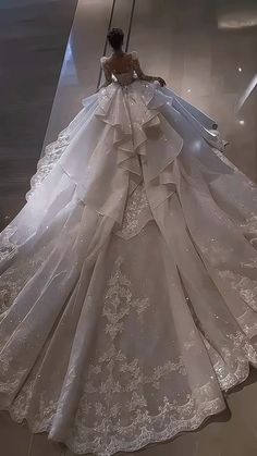 a woman in a white wedding dress is walking down the stairs with her back to the camera