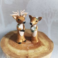 two small deer figurines sitting on top of a piece of wood