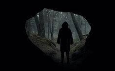 a person standing in the middle of a dark forest