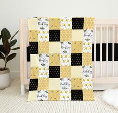 a baby crib bed with a yellow and black quilt on the side, next to a potted plant