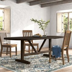 a dining room table with chairs and a rug in front of the table is shown