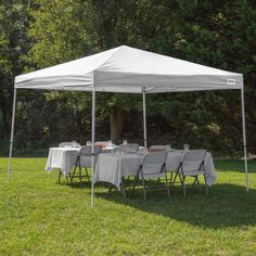 a blue and white tent is set up in the grass for an outdoor dinner party