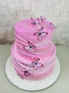 a cake with pink frosting and butterflies on it