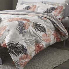 a bed with an orange and black palm leaf comforter set on top of it