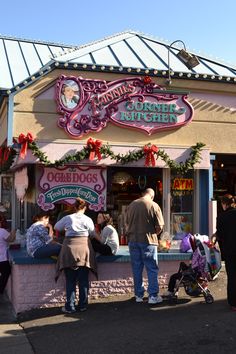 people standing in line at a candy shop with christmas decorations on the front and side