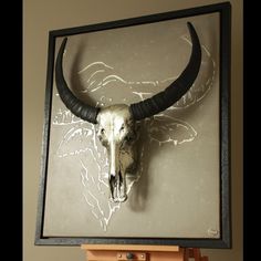 a bull's skull mounted on the wall in front of a wooden easel