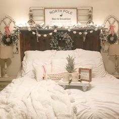 a bed with white blankets and christmas lights on the headboard, along with other holiday decorations