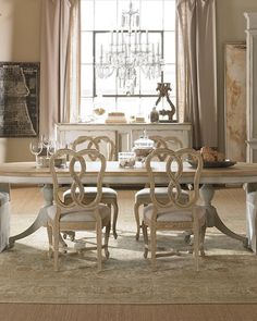 a dining room table with chairs and a chandelier hanging from the ceiling in front of a window