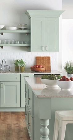 a kitchen filled with lots of green cabinets and white counter top space next to a wooden floor