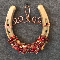 a horseshoe shaped brooch with red beads and metal wire attached to it's sides