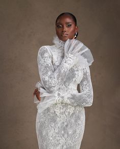 a woman in a white lace dress poses for the camera with her hands on her hips