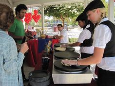 some people are standing at a table with plates and pans in front of them