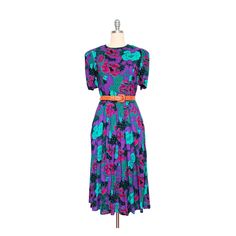 "This bold and vibrant vintage dress features 2 side pockets, round neck, pleated short sleeves and partial elastic waist.  𝘿𝙀𝙏𝘼𝙄𝙇𝙎  ▻ LABEL: Jessica Howard by Mitchell Rodbell Petite ▻ CONDITION: Excellent ▻ MATERIAL: 100% Rayon ▻ CLOSURE: Button up back, zipper waist, hook & eye  ▻ COLORS: Purple, magenta/hot pink, teal/aqua, & black ▻ SIZE: 10 on label. Fits up to a size Medium, depending on desired fit. ▻ MEASUREMENTS: Bust: 36\" | Waist: 28\" | Sleeve Length: 11.5\" | Length: 46″ | S Retro Short Sleeve Dress With Pleated Waist, Floral Flared Dress, Pineapple Dress, Gingham Pants, Floral Pattern Dress, Midi Flare Skirt, Micro Mini Skirt, Floral Sheath Dress, Purple Turquoise