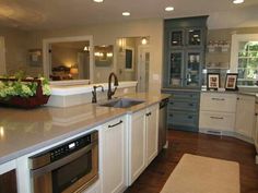 a kitchen with white cabinets and an island in the middle is lit by recessed lights