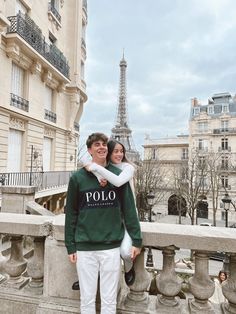 two people standing next to each other in front of the eiffel tower