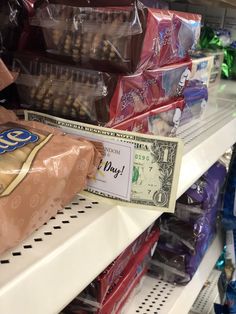 a dollar bill is on the shelf in a grocery store as other items are stacked up behind it