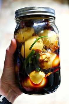 a person holding up a jar filled with food