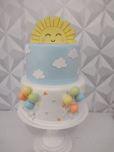 a three tiered cake with balloons and a sun on top