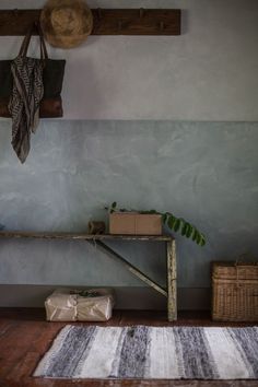 a room with a rug, shelf and basket on the floor next to wall mounted hooks