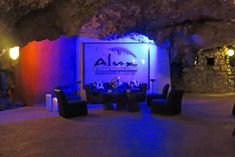 people are sitting at tables in front of a blue and red lit cave with palm trees