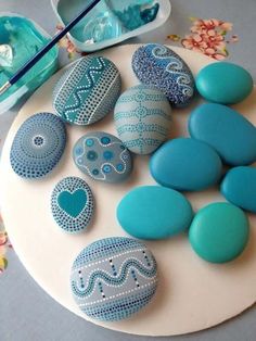 blue and white decorated rocks on a plate with spoons next to it, along with other decorative items