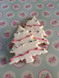 decorated cookies in the shape of christmas trees on a tablecloth with pink and blue flowers