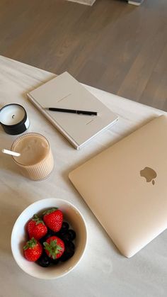 an apple laptop, strawberries and coffee on a table