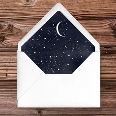 an open envelope with a black and white design on it, against a wooden background