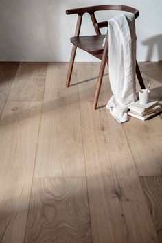 a wooden chair sitting on top of a hard wood floor next to a white towel