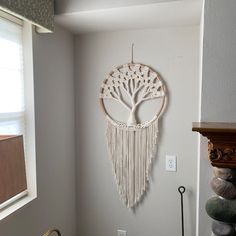 a white wall hanging with a tree on it's side next to a window