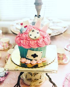 a cupcake decorated with pink and blue icing on top of a cake plate