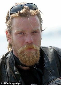 a man with a beard wearing sunglasses and a leather jacket is looking at the camera