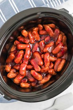 a crock pot filled with hot dogs covered in ketchup