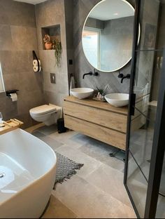 a modern bathroom with two sinks and a large round mirror above the bathtub, along with a walk in shower