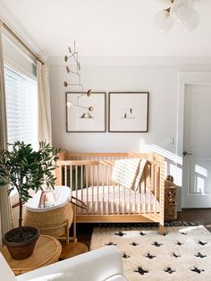 a baby's room with a crib, chair, and potted plant