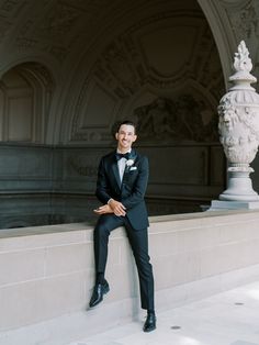 a man in a tuxedo leaning against a wall