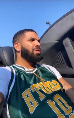 a man sitting in the back seat of a car wearing a green and white shirt