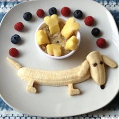 a white plate topped with fruit and a dog cut out in the shape of a banana