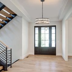 an empty entryway with stairs and chandelier