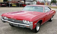 an old red car parked in a parking lot